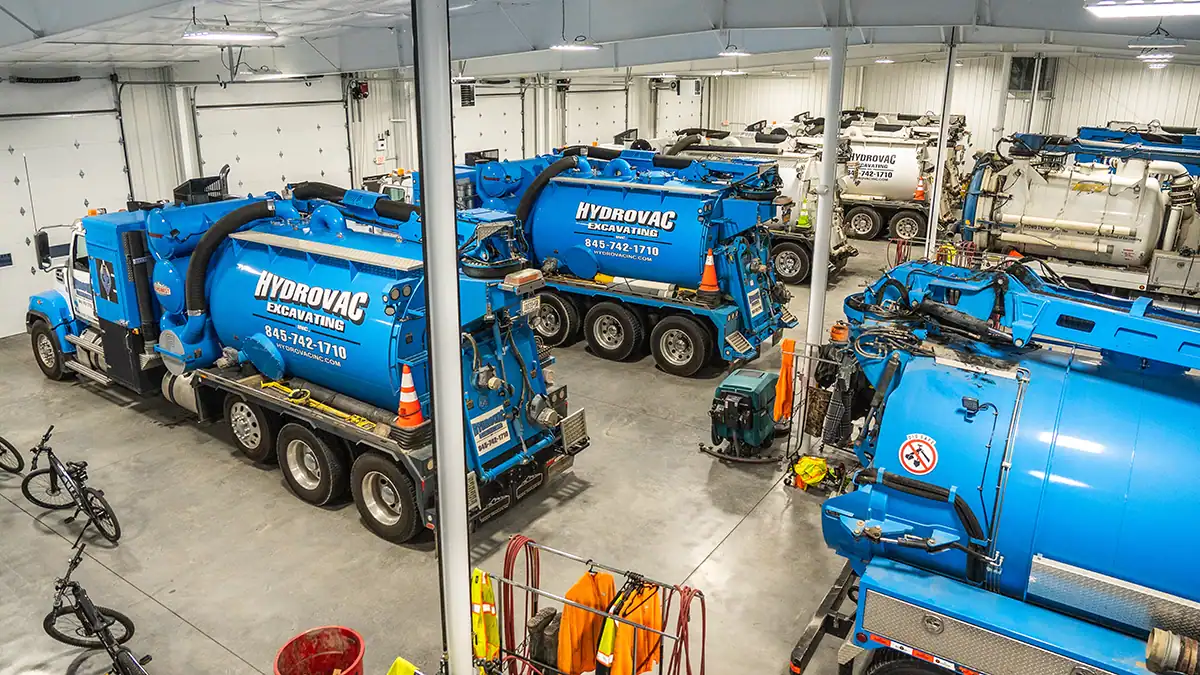 A large group of Hydrovac Excavating trucks in a warehouse.