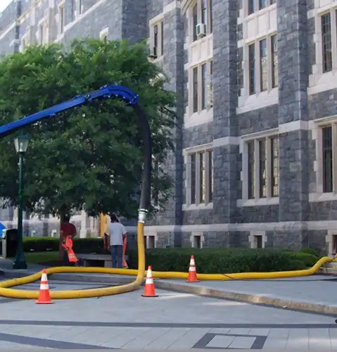 Two men in safety vests using remote hose to reach an apartment building.