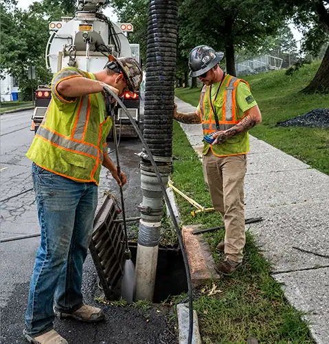 Two men in safety vests using Hydrovac directional boring to dig on s street.