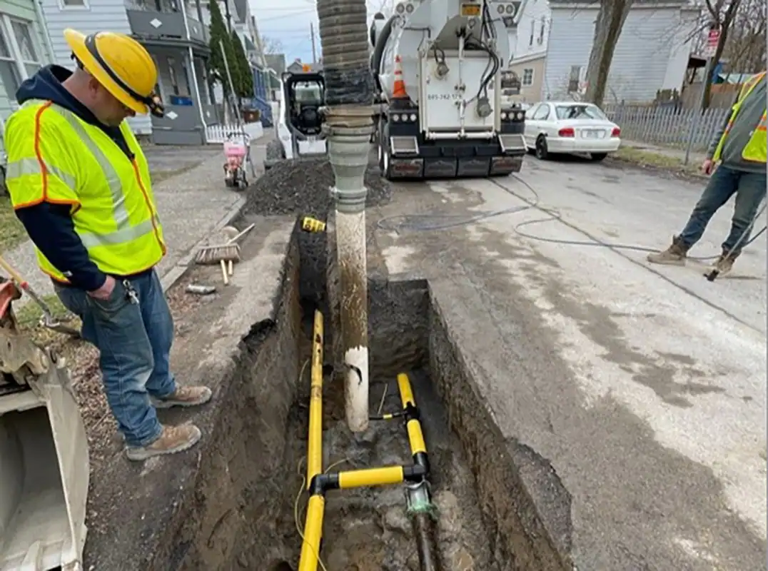 A man in a yellow vest watching Hydrovac excavation.