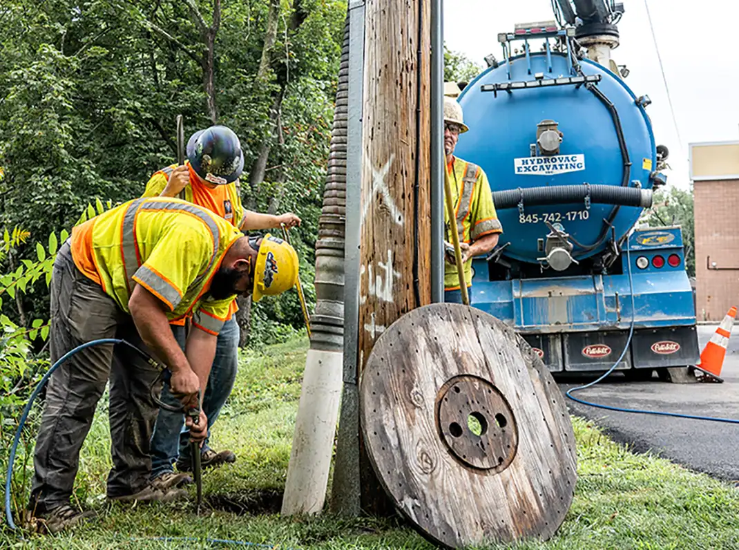 Hydrovac Excavating crew performing daylighting around a utility pole in the Hudson Valley using pressurized water and vacuum equipment.